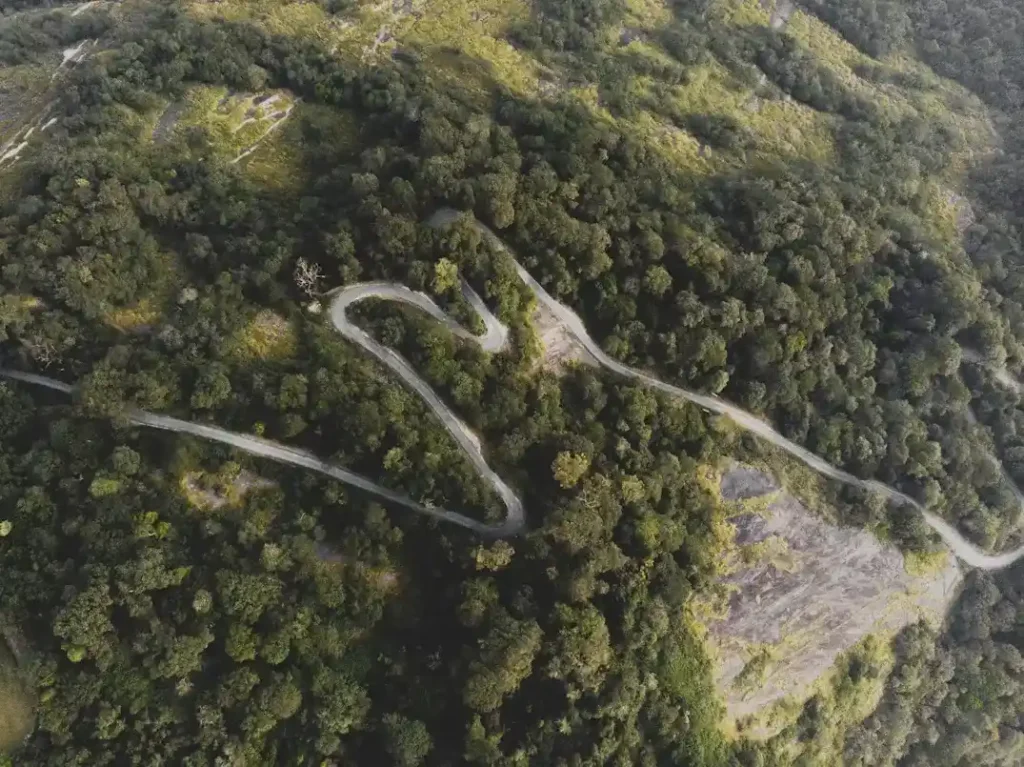 Aerial view of winding mountain roads in Agumbe surrounded by dense green forest during monsoon in India.